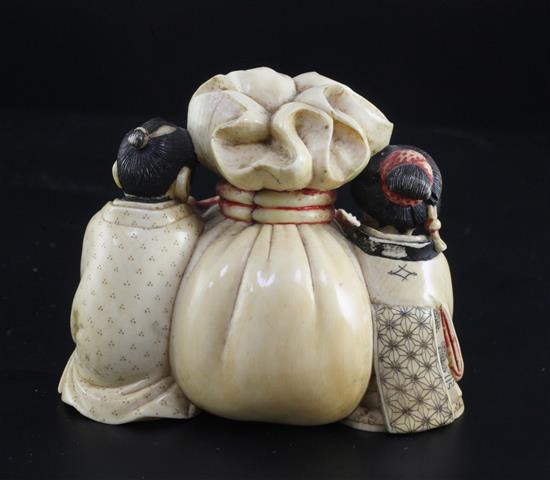 A Japanese ivory okimono of a man and woman holding the cords of a tied sack between them, Meiji period, width 7.3cm